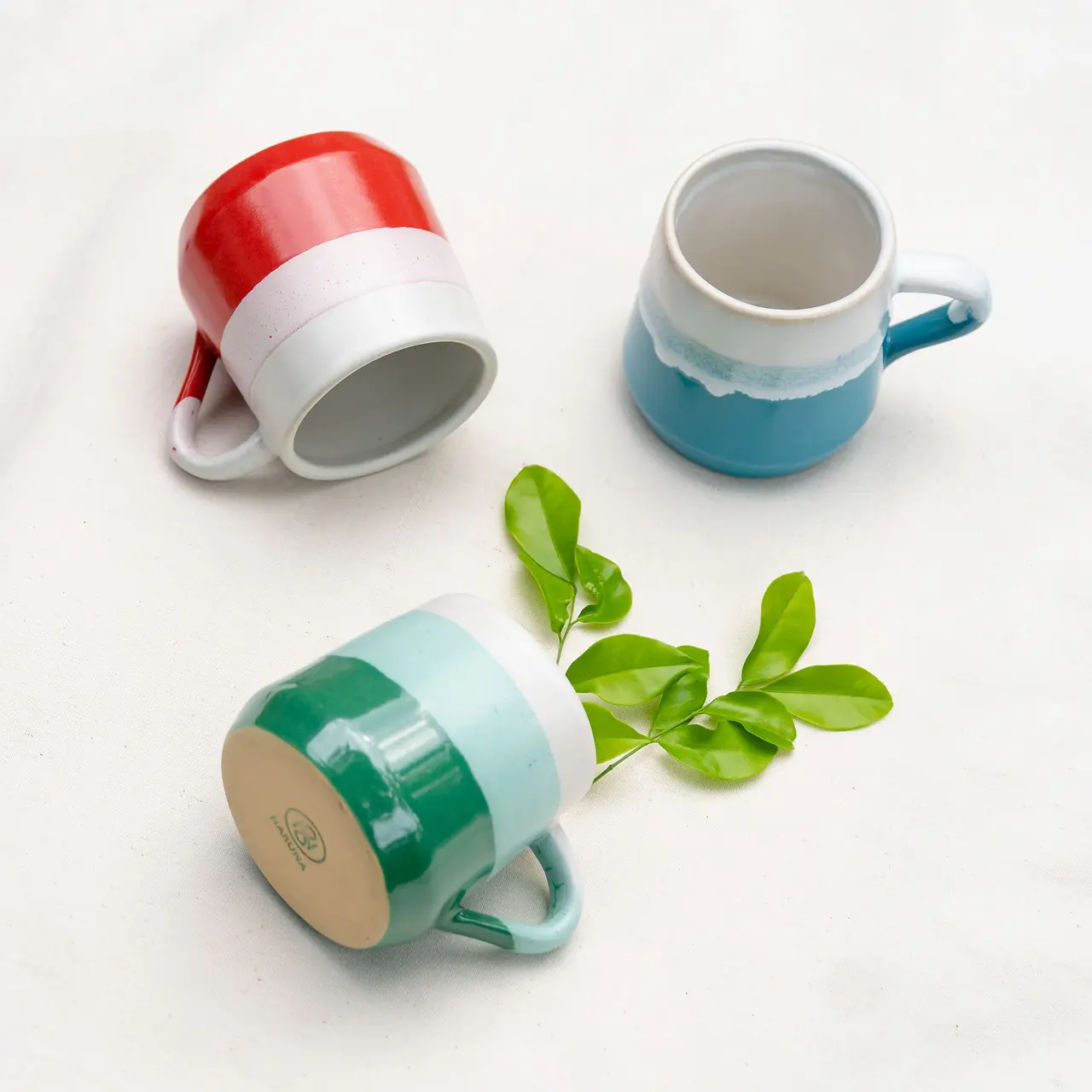 Tiga mug keramik berwarna-warni