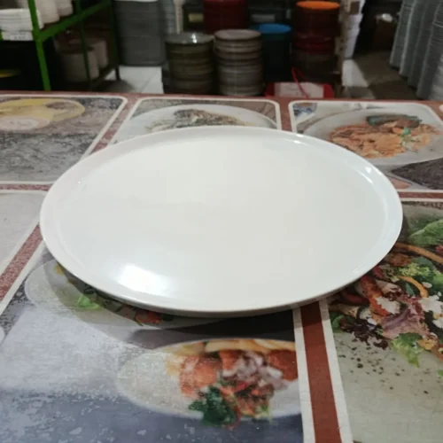 Piring putih datar di atas taplak meja