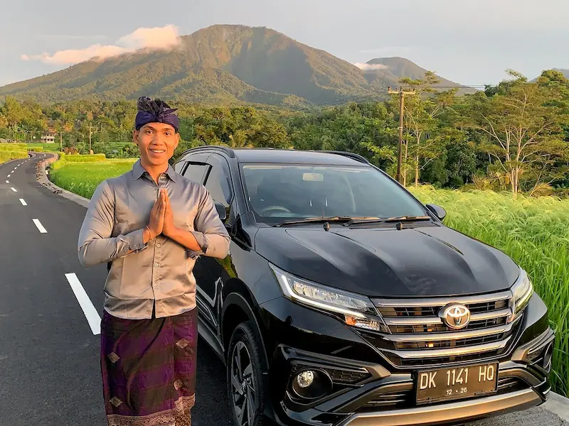 Pria Bali menyambut di samping mobil
