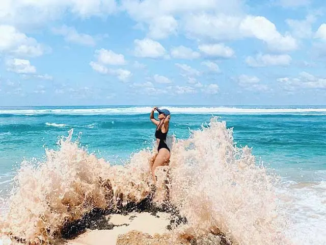 Wanita di pantai saat ombak